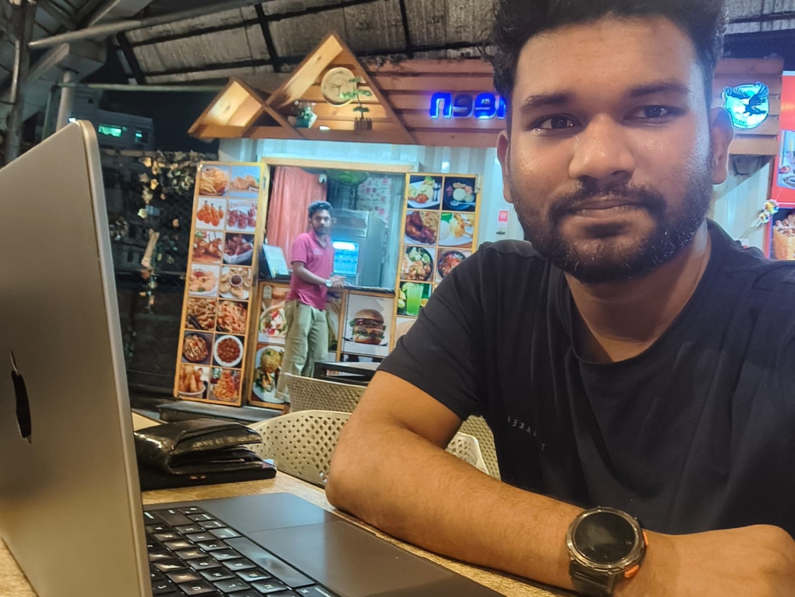 Api Alam working on a laptop at an outdoor table while building a startup